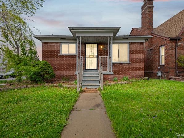 Front view of a brick home with steps and greenery, located in Detroit.