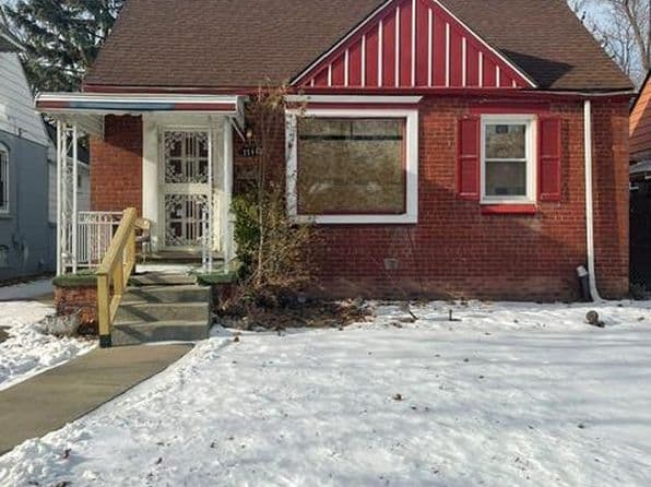 Brick home with a red accent, porch, and snow-covered yard