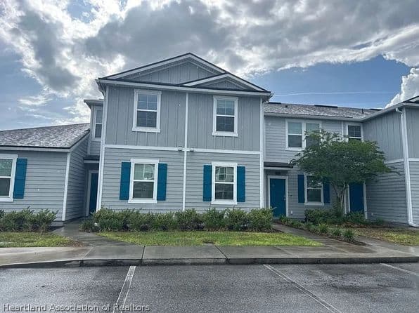 Exterior view of a gray multi-unit home with blue shutters.